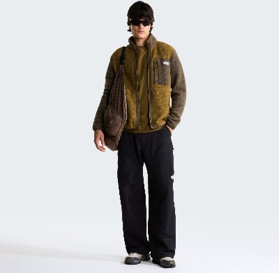 Mann in olivgrüner Fleecejacke und schwarzer Hose mit Umhängetasche. Mann in olivgrüner Fleecejacke und schwarzer Hose mit Umhängetasche.