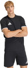 Ein Mann in einem schwarzen T-Shirt und Shorts mit Adidas-Logo steht mit verschränkten Armen.