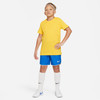 Junge in gelbem T-Shirt, blauer Hose und weißen Socken.