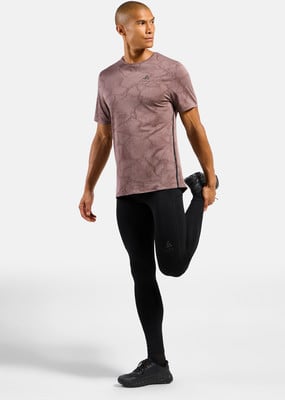 Ein Mann in einem rosafarbenen Shirt und schwarzer Leggings dehnt sich. Ein Mann in einem rosafarbenen Shirt und schwarzer Leggings dehnt sich.