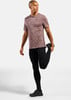 Ein Mann in einem rosafarbenen Shirt und schwarzer Leggings dehnt sich.