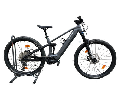 Graues E-Bike mit Federung auf Ständer, weißer Hintergrund.