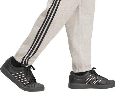 Graue Jogginghose mit schwarzen Streifen und schwarzen Adidas-Sneakern