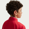 Detail des Kopfes und Nackens eines Jungen mit lockigem Haar in einer roten Jacke.
