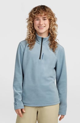 Junges Mädchen mit lockigem Haar in einem blauen Fleece-Pullover mit kurzem Reißverschluss. Junges Mädchen mit lockigem Haar in einem blauen Fleece-Pullover mit kurzem Reißverschluss.