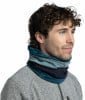 Ein Mann in einem grauen Pullover mit einem mehrfarbigen Schlauchschal und lockigem Haar.