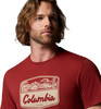 Ein Mann in einem roten T-Shirt mit einem Landschaftsdruck und dem Columbia-Schriftzug.