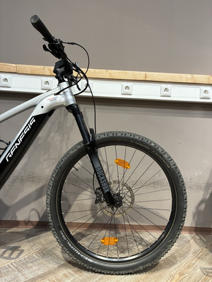 Vorderseite eines Genesis Mountainbikes mit RockShox-Federung und Reflektoren. Vorderseite eines Genesis Mountainbikes mit RockShox-Federung und Reflektoren.
