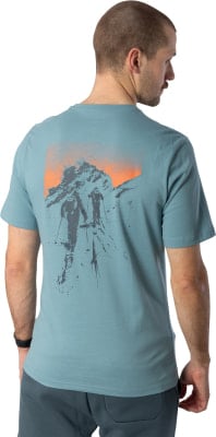 Ein Mann trägt ein T-Shirt mit einem Aufdruck von Bergsteigern in den Bergen. Ein Mann trägt ein T-Shirt mit einem Aufdruck von Bergsteigern in den Bergen.