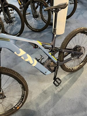 Ein blaues Mountain-E-Bike mit Federung und schwarzen Rädern auf einem blauen Teppich. Ein blaues Mountain-E-Bike mit Federung und schwarzen Rädern auf einem blauen Teppich.