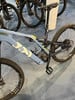 Ein blaues Mountain-E-Bike mit Federung und schwarzen Rädern auf einem blauen Teppich.