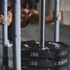 Eine Frau schiebt einen Schlitten mit Gewichten im Fitnessstudio, Fokus auf die Gewichte.