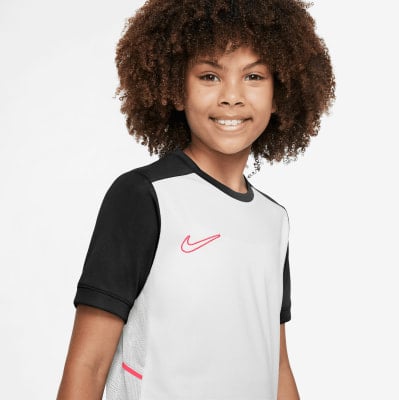 Junge in einem weißen T-Shirt mit schwarzen Ärmeln und einem rosa Nike-Logo. Junge in einem weißen T-Shirt mit schwarzen Ärmeln und einem rosa Nike-Logo.