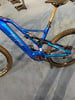 Ein blaues Fullsuspension-Mountainbike mit goldener Sattelstütze.