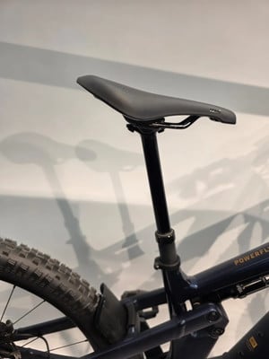 Eine Sattelstütze mit schwarzem Sattel an einem dunkelblauen E-Bike.
