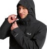 Ein Mann passt die Kapuze einer schwarzen wasserdichten Jacke mit Jack Wolfskin-Logo an.