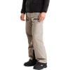 Ein Mann trägt eine beige Hose mit schwarzen Reißverschlüssen und schwarze Stiefel.