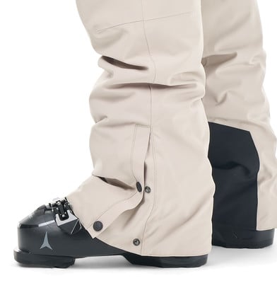 Beige Skihose mit schwarzem Einsatz und Schnallen an Skischuhen. Beige Skihose mit schwarzem Einsatz und Schnallen an Skischuhen.