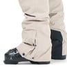 Beige Skihose mit schwarzem Einsatz und Schnallen an Skischuhen.