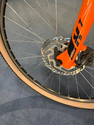 Detail eines orangefarbenen Fahrradvorderrads mit Scheibenbremse. Detail eines orangefarbenen Fahrradvorderrads mit Scheibenbremse.