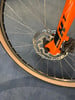 Detail eines orangefarbenen Fahrradvorderrads mit Scheibenbremse.