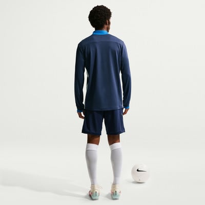 Ein Mann in dunkelblauem Fußballtrikot und Shorts steht mit einem Ball. Ein Mann in dunkelblauem Fußballtrikot und Shorts steht mit einem Ball.