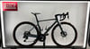Ein graues Scott Rennrad mit braunen Felgen auf einem Ständer.
