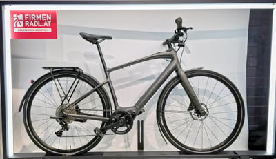 Graues Herren-E-Bike mit Ständer und Logo an der Wand. Graues Herren-E-Bike mit Ständer und Logo an der Wand.
