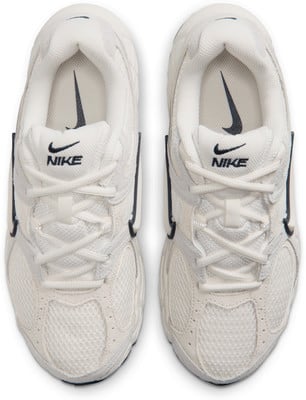Fehér Nike cipők fekete logóval és fűzőkkel, felülnézet. Fehér Nike cipők fekete logóval és fűzőkkel, felülnézet.