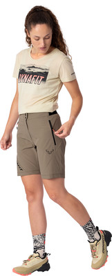 Eine Frau in einem beigen T-Shirt und Khaki-Shorts mit schwarzen Reißverschlüssen und Schuhen. Eine Frau in einem beigen T-Shirt und Khaki-Shorts mit schwarzen Reißverschlüssen und Schuhen.