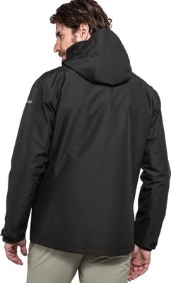 Ein Mann in einer schwarzen Kapuzenjacke und beige Hose blickt über die Schulter. Ein Mann in einer schwarzen Kapuzenjacke und beige Hose blickt über die Schulter.