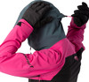 Eine Person passt die Kapuze einer Skijacke mit pinken Ärmeln und schwarzen Handschuhen an.