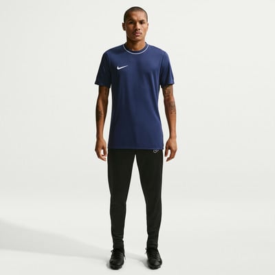 Ein Mann in einem dunkelblauen Nike-T-Shirt und schwarzer Hose steht. Ein Mann in einem dunkelblauen Nike-T-Shirt und schwarzer Hose steht.