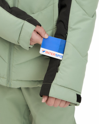 Eine Hand steckt eine Intersport-Karte in eine Ärmeltasche einer Skijacke.