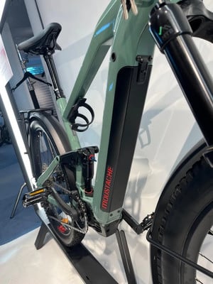 Grünes E-Bike mit Federung und schwarzem Akku am Rahmen. Grünes E-Bike mit Federung und schwarzem Akku am Rahmen.