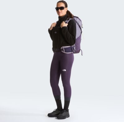 Eine Frau in dunklen Leggings und Jacke mit Rucksack. Eine Frau in dunklen Leggings und Jacke mit Rucksack.