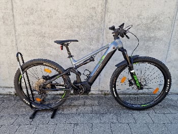 Genesis E-Mountainbike mit Federung und Schutzblechen auf einem Ständer.