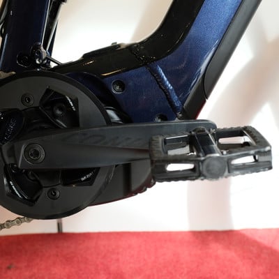 Nahaufnahme von Kurbel und Pedal eines dunkelblauen E-Bikes. Nahaufnahme von Kurbel und Pedal eines dunkelblauen E-Bikes.