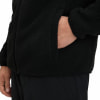 Detail einer schwarzen Fleecejacke mit einer Hand in der Tasche.
