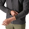 Ein Mann passt den Ärmel einer dunklen Jacke mit gerippten Bündchen an.
