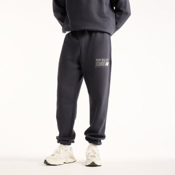 Ein Mann trägt eine dunkelblaue Jogginghose mit New Balance Logo und weiße Sneaker.