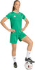 Frau im grünen Fußballtrikot und Shorts mit Ball.