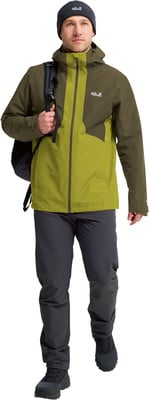 Ein Mann in einer grünen Jacke und dunkler Hose mit Rucksack. Ein Mann in einer grünen Jacke und dunkler Hose mit Rucksack.