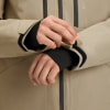 Ein Mann schließt den Ärmel einer Jacke mit Klettverschluss, schwarze Innenmanschette sichtbar.