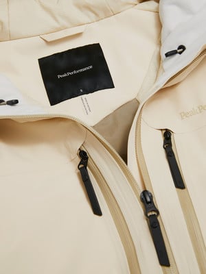 Detail eines Etiketts mit dem Peak Performance Logo und Größe S auf einer beigen Jacke. Detail eines Etiketts mit dem Peak Performance Logo und Größe S auf einer beigen Jacke.