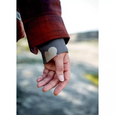 Eine Hand mit einem Pulloverärmel mit Herz am Handgelenk. Eine Hand mit einem Pulloverärmel mit Herz am Handgelenk.