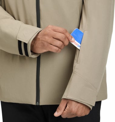 Ein Mann in einer beige Jacke steckt eine Karte in eine Ärmeltasche. Ein Mann in einer beige Jacke steckt eine Karte in eine Ärmeltasche.