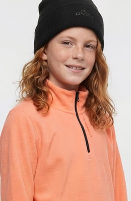 Ein Mädchen mit roten Haaren in einem orangefarbenen Fleece-Pullover und schwarzer Mütze. Ein Mädchen mit roten Haaren in einem orangefarbenen Fleece-Pullover und schwarzer Mütze.