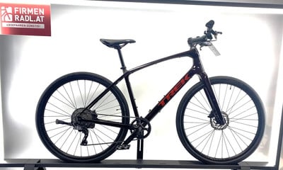Ein rotes Trek-Fahrrad auf einem schwarzen Ständer mit Firmenlogo Ein rotes Trek-Fahrrad auf einem schwarzen Ständer mit Firmenlogo