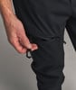 Eine Männerhand hält einen Karabiner an einer schwarzen Kordel an einer Hose.